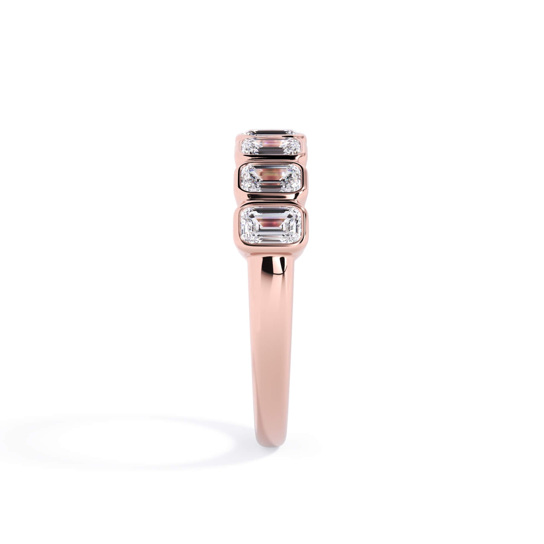 A picture of a seven stone diamond wedding ring with emerald cut diamonds that are bezel set in rose gold on a white background with a side profile view.