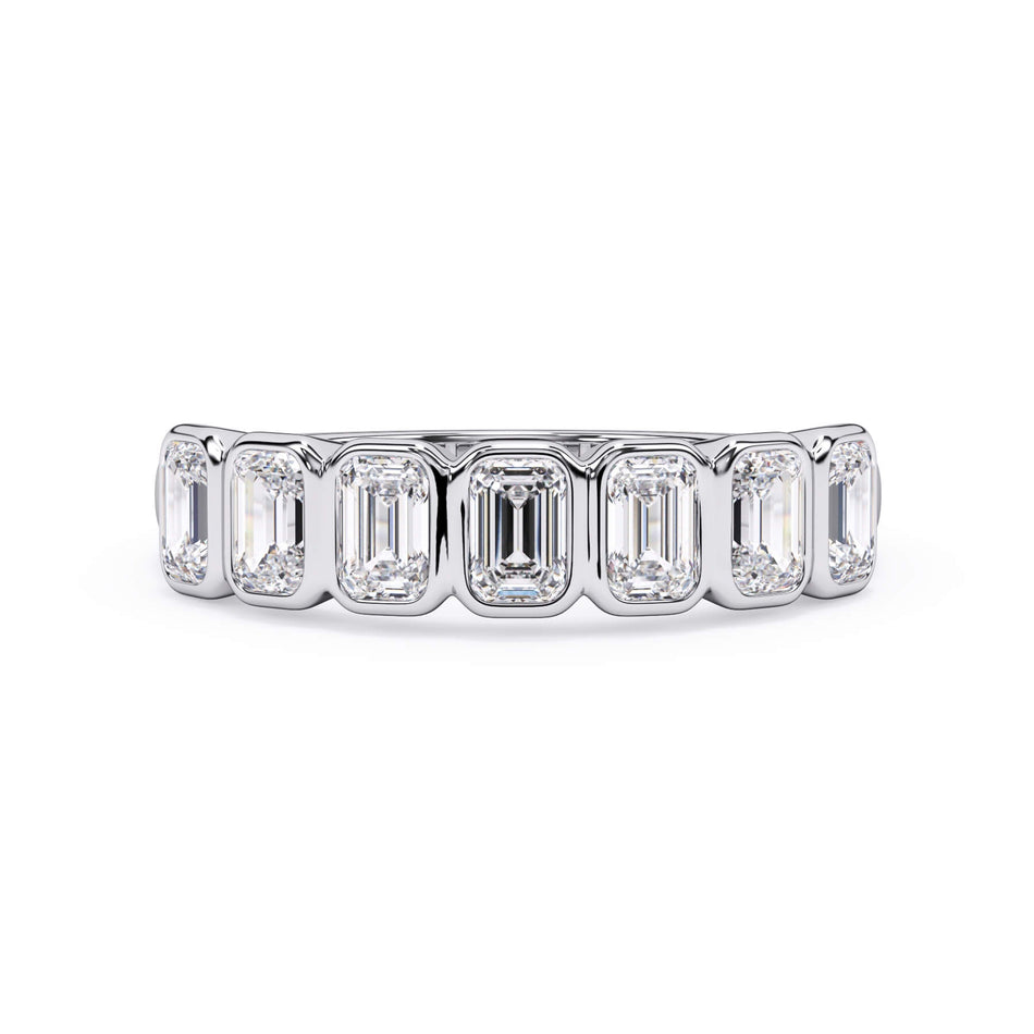A picture of a seven stone diamond wedding ring with emerald cut diamonds that are bezel set in white gold or platinum on a white background with the ring facing forward, lying down.