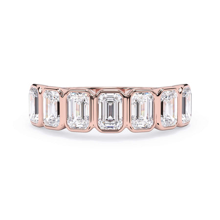 A picture of a seven stone diamond wedding ring with emerald cut diamonds that are bezel set in rose gold on a white background with the ring facing forward, lying down.