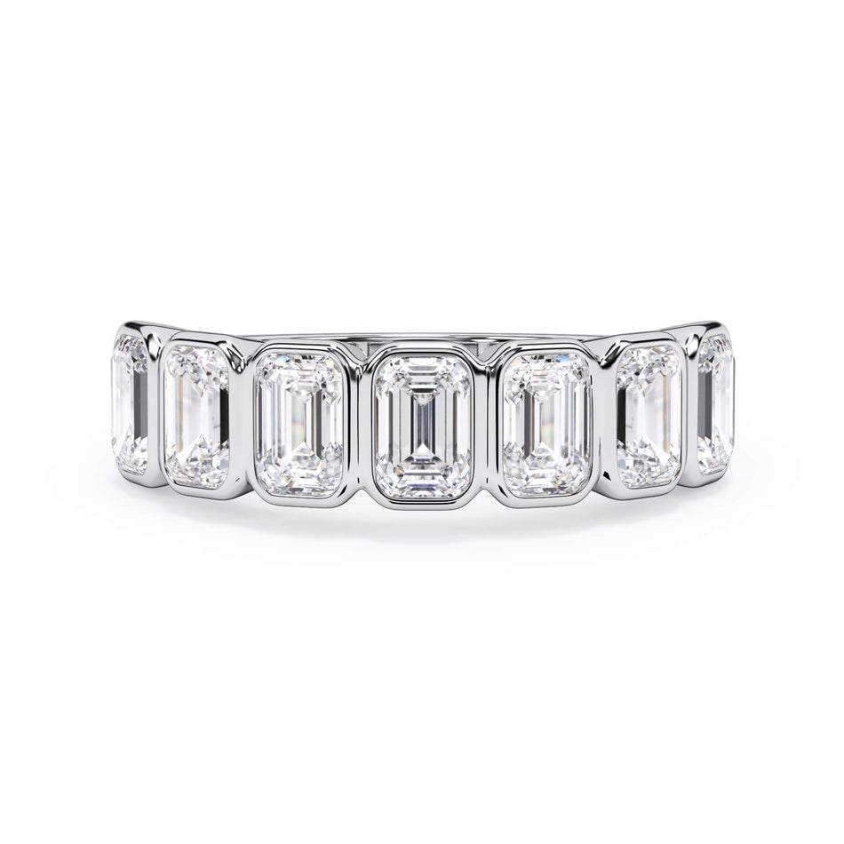 A picture of a seven stone diamond wedding ring with emerald cut diamonds that are bezel set in white gold or platinum on a white background with the ring facing forward, lying down.