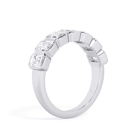 A picture of a seven stone diamond wedding ring with emerald cut diamonds that are bezel set in white gold or platinum on a white background with a slightly angled, through the finger view.