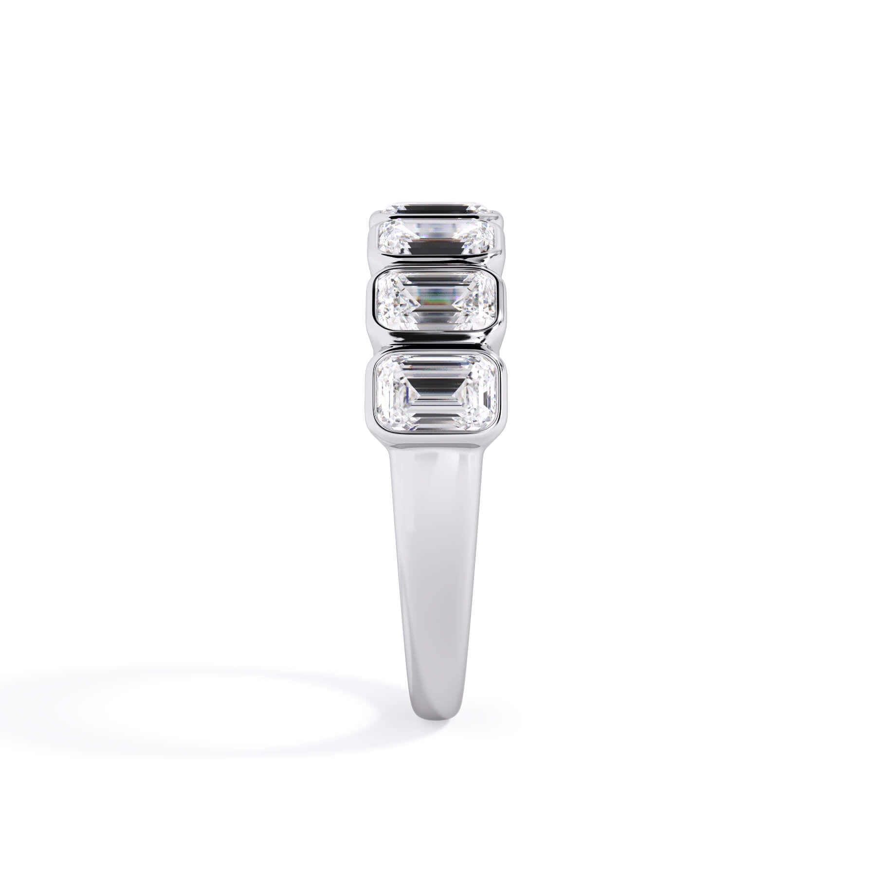 A picture of a seven stone diamond wedding ring with emerald cut diamonds that are bezel set in white gold or platinum on a white background with a side profile view.