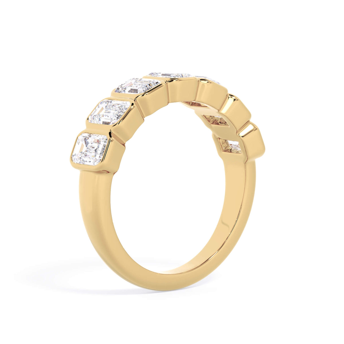 A picture of a seven stone diamond wedding ring with emerald cut diamonds that are bezel set in yellow gold on a white background with a slightly angled, through the finger view.