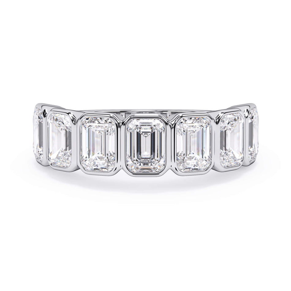 A picture of a seven stone diamond wedding ring with emerald cut diamonds that are bezel set in white gold or platinum on a white background with the ring facing forward, lying down.