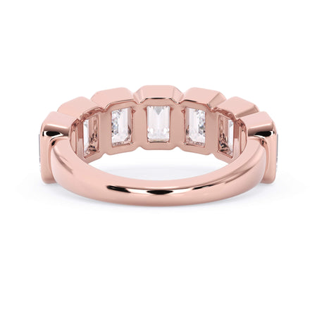 A picture of a seven stone diamond wedding ring with emerald cut diamonds that are bezel set in rose gold on a white background with a view of the underside of the ring.