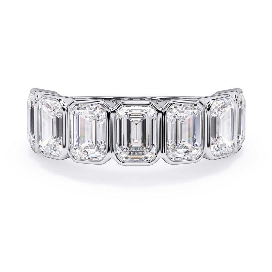 A picture of a seven stone diamond wedding ring with emerald cut diamonds that are bezel set in white gold or platinum on a white background with the ring facing forward, lying down.