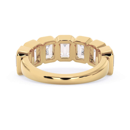 A picture of a seven stone diamond wedding ring with emerald cut diamonds that are bezel set in yellow gold on a white background with a view of the underside of the ring.