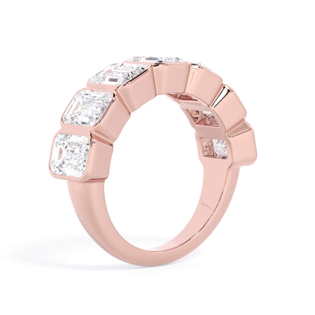 A picture of a seven stone diamond wedding ring with emerald cut diamonds that are bezel set in rose gold on a white background with a slightly angled, through the finger view.