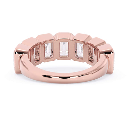 A picture of a seven stone diamond wedding ring with emerald cut diamonds that are bezel set in rose gold on a white background with a view of the underside of the ring.