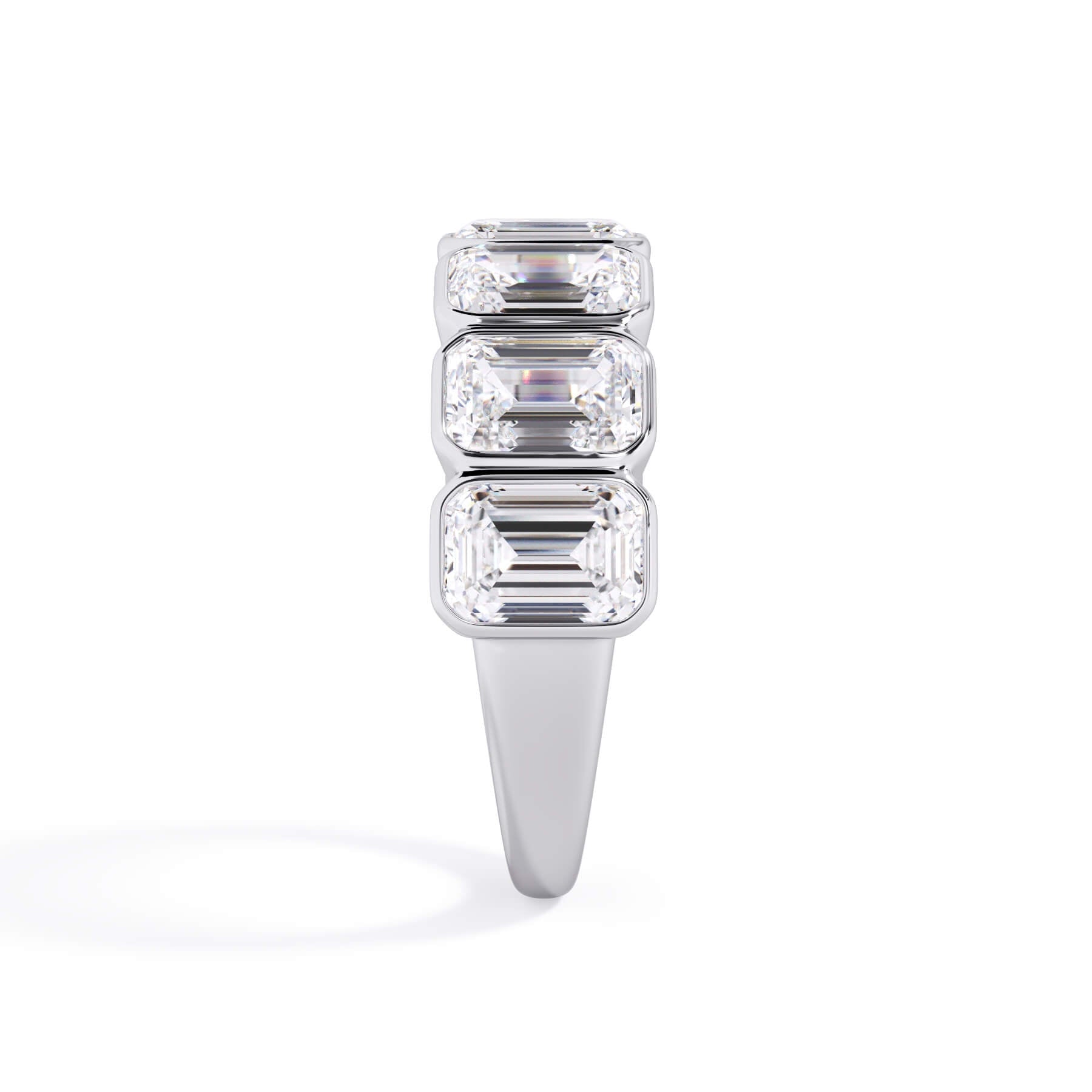 A picture of a seven stone diamond wedding ring with emerald cut diamonds that are bezel set in white gold or platinum on a white background with a side profile view.