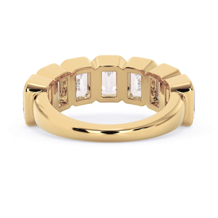 A picture of a seven stone diamond wedding ring with emerald cut diamonds that are bezel set in yellow gold on a white background with a view of the underside of the ring.
