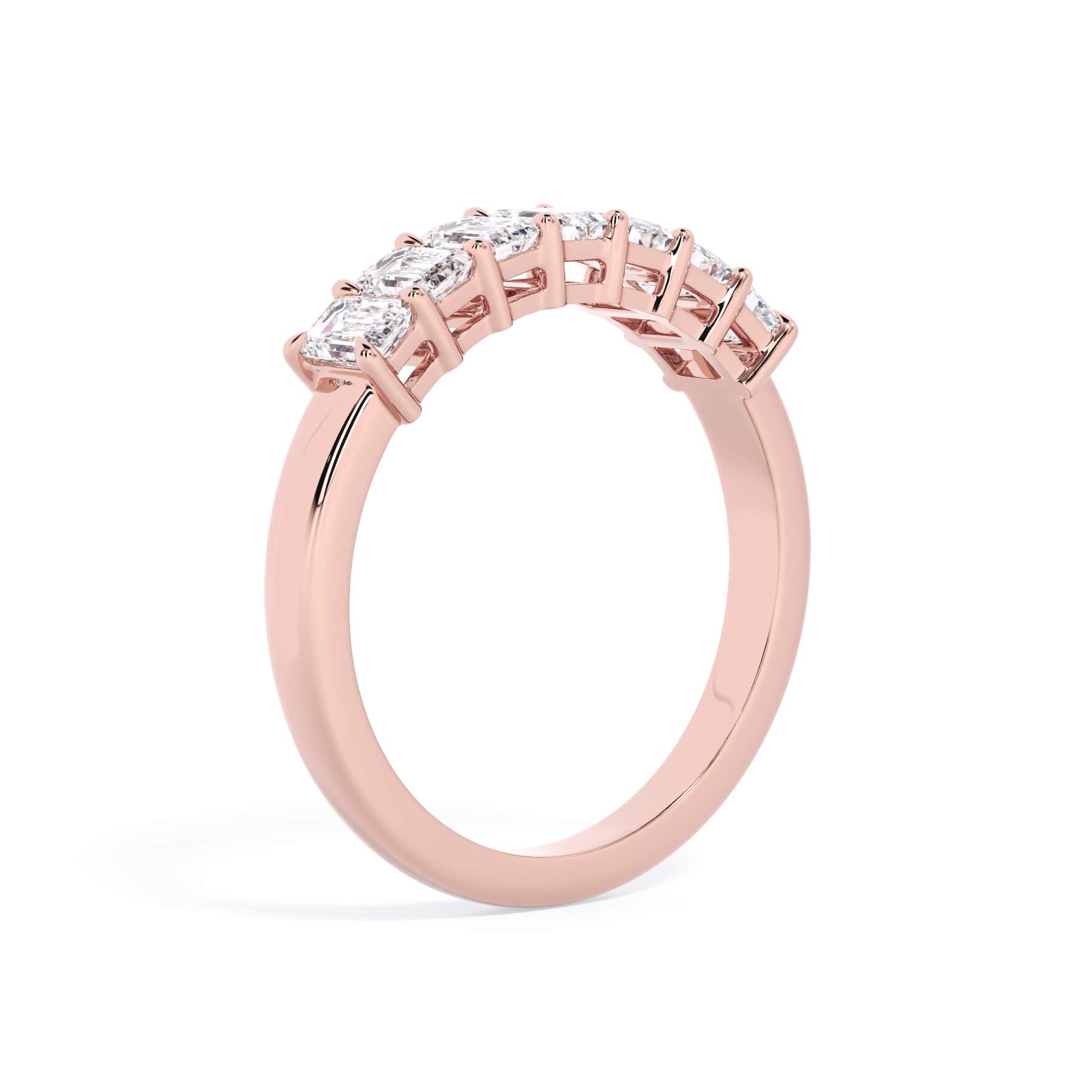 A picture of a seven stone diamond wedding ring with emerald cut diamonds that are shared prong set in rose gold on a white background with a slightly angled, through the finger view.