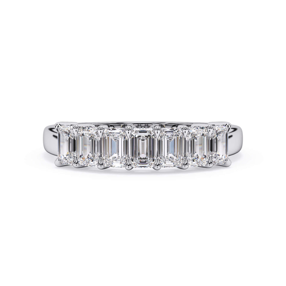 A picture of a seven stone diamond wedding ring with emerald cut diamonds that are shared prong set in white gold or platinum on a white background with the ring facing forward, lying down.