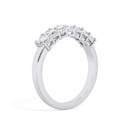 A picture of a seven stone diamond wedding ring with emerald cut diamonds that are shared prong set in white gold or platinum on a white background with a slightly angled, through the finger view.