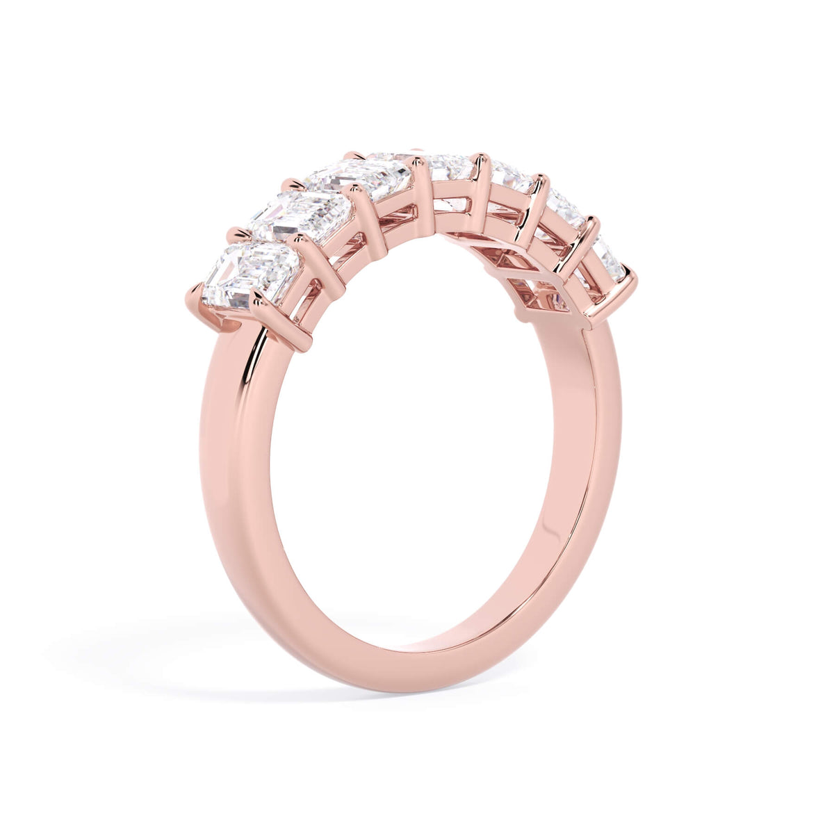 A picture of a seven stone diamond wedding ring with emerald cut diamonds that are shared prong set in rose gold on a white background with a slightly angled, through the finger view.
