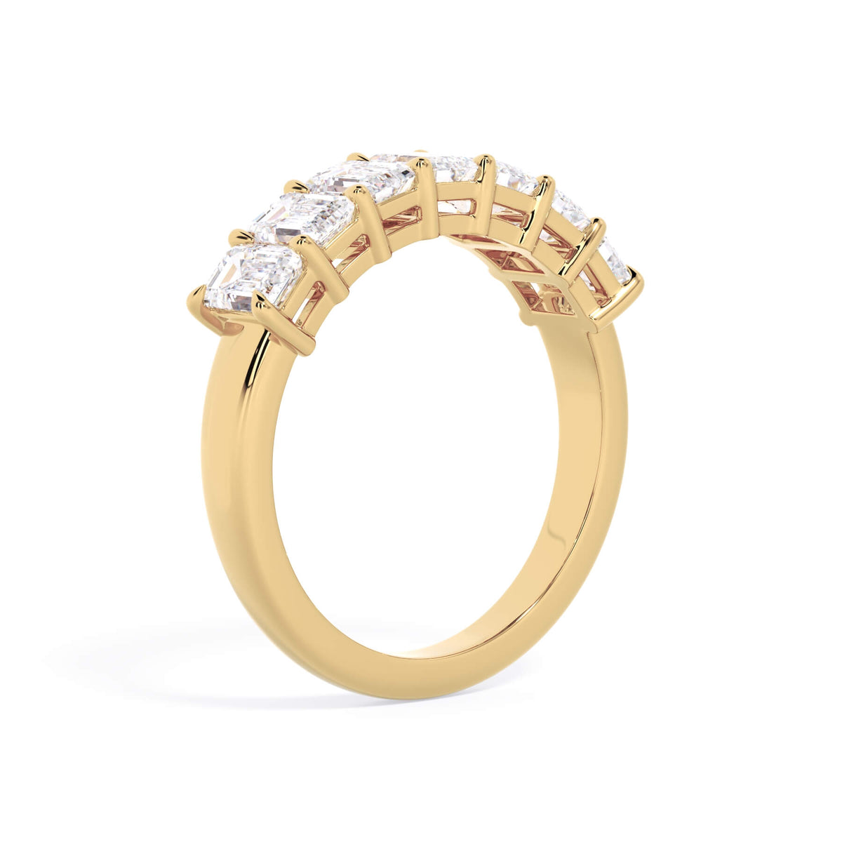 A picture of a seven stone diamond wedding ring with emerald cut diamonds that are shared prong set in yellow gold on a white background with a slightly angled, through the finger view.
