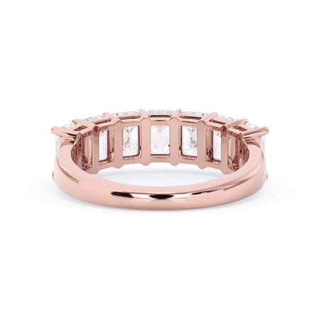 A picture of a seven stone diamond wedding ring with emerald cut diamonds that are shared prong set in rose gold on a white background with a view of the underside of the ring.