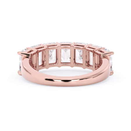 A picture of a seven stone diamond wedding ring with emerald cut diamonds that are shared prong set in rose gold on a white background with a view of the underside of the ring.