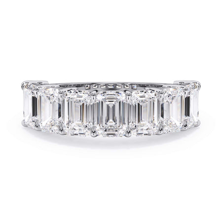 A picture of a seven stone diamond wedding ring with emerald cut diamonds that are shared prong set in white gold or platinum on a white background with the ring facing forward, lying down.