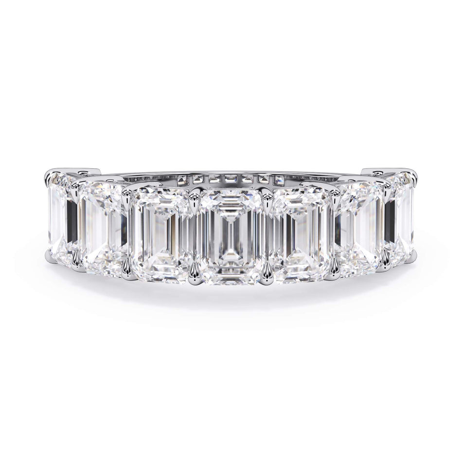 A picture of a seven stone diamond wedding ring with emerald cut diamonds that are shared prong set in white gold or platinum on a white background with the ring facing forward, lying down.