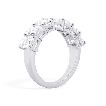 A picture of a seven stone diamond wedding ring with emerald cut diamonds that are shared prong set in white gold or platinum on a white background with a slightly angled, through the finger view.