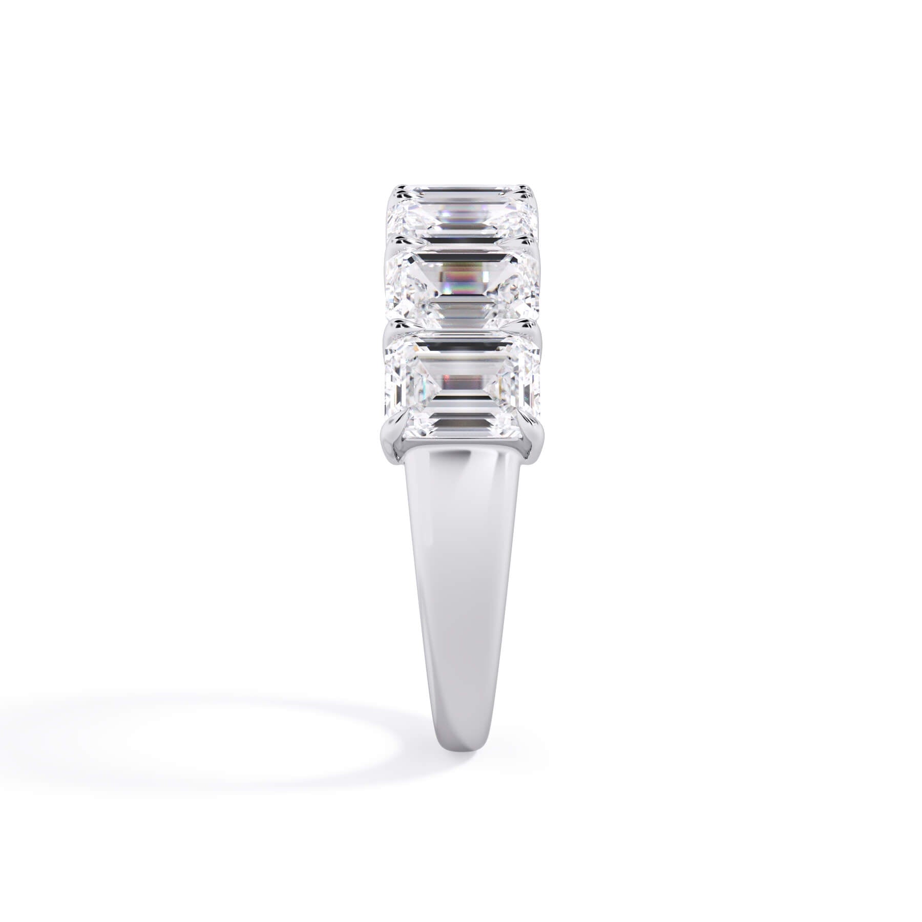 A picture of a seven stone diamond wedding ring with emerald cut diamonds that are shared prong set in white gold or platinum on a white background with a side profile view.