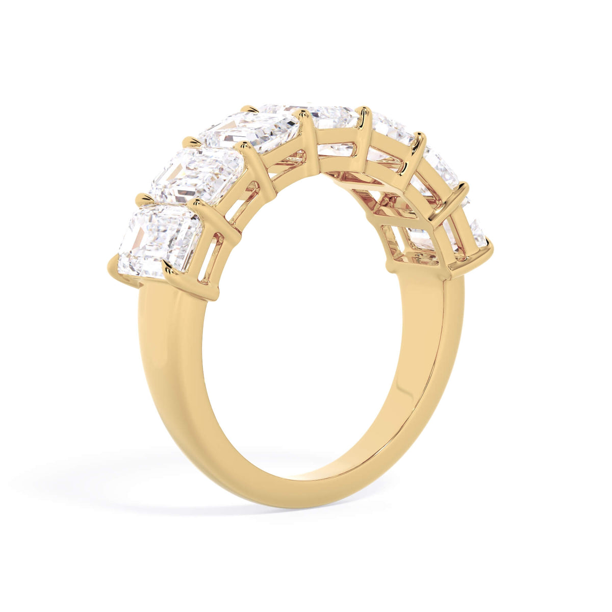 A picture of a seven stone diamond wedding ring with emerald cut diamonds that are shared prong set in yellow gold on a white background with a slightly angled, through the finger view.