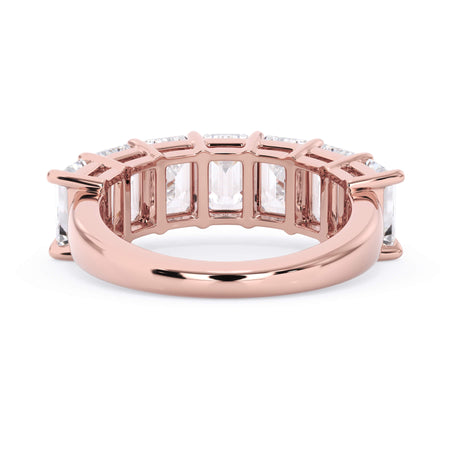 A picture of a seven stone diamond wedding ring with emerald cut diamonds that are shared prong set in rose gold on a white background with a view of the underside of the ring.