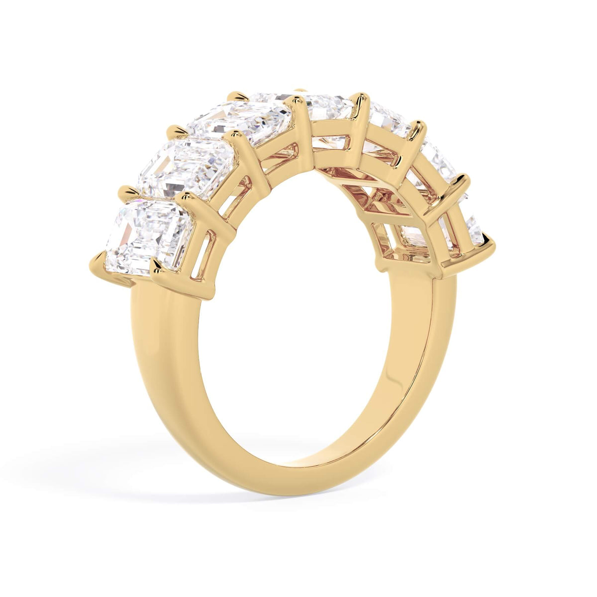 A picture of a seven stone diamond wedding ring with emerald cut diamonds that are shared prong set in yellow gold on a white background with a slightly angled, through the finger view.