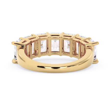 A picture of a seven stone diamond wedding ring with emerald cut diamonds that are shared prong set in yellow gold on a white background with a view of the underside of the ring.