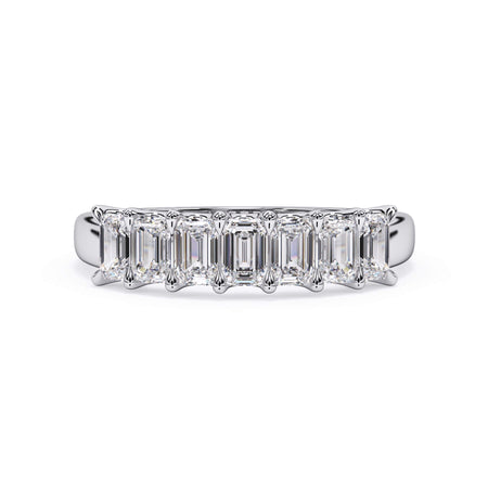 A picture of a seven stone diamond wedding ring with emerald cut diamonds that are U prong set in white gold or platinum on a white background with the ring facing forward, lying down.