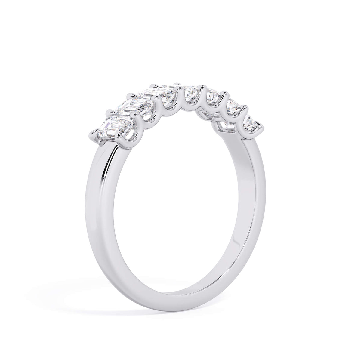 A picture of a seven stone diamond wedding ring with emerald cut diamonds that are U prong set in white gold or platinum on a white background with a slightly angled, through the finger view.