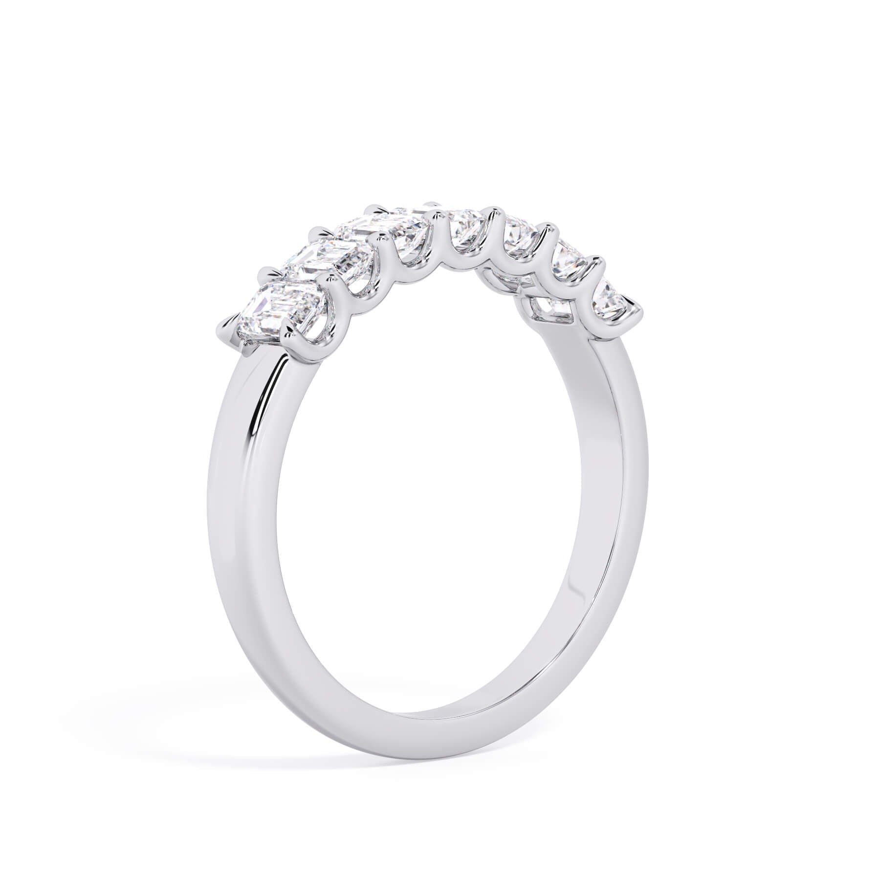 A picture of a seven stone diamond wedding ring with emerald cut diamonds that are U prong set in white gold or platinum on a white background with a slightly angled, through the finger view.