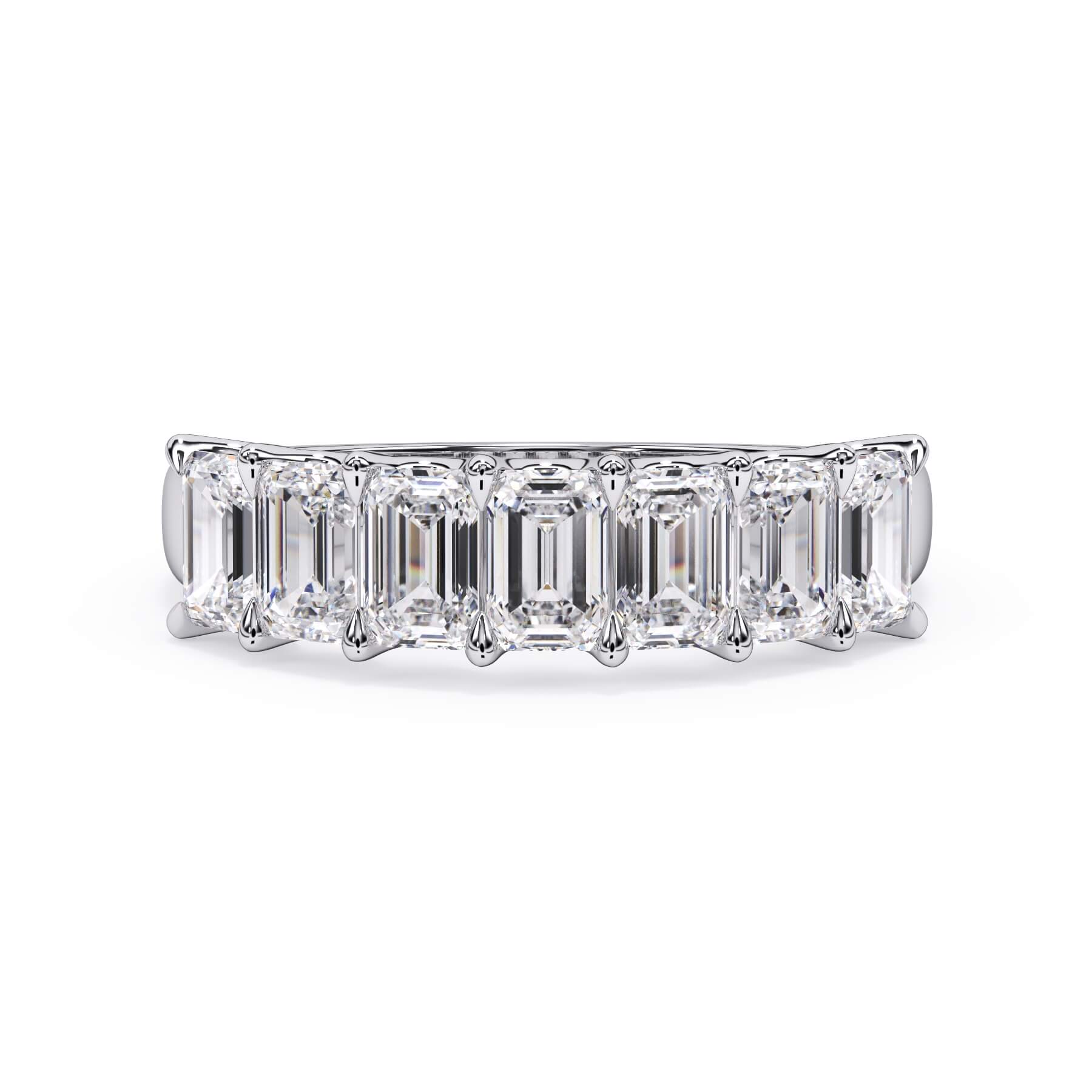 A picture of a seven stone diamond wedding ring with emerald cut diamonds that are U prong set in white gold or platinum on a white background with the ring facing forward, lying down.