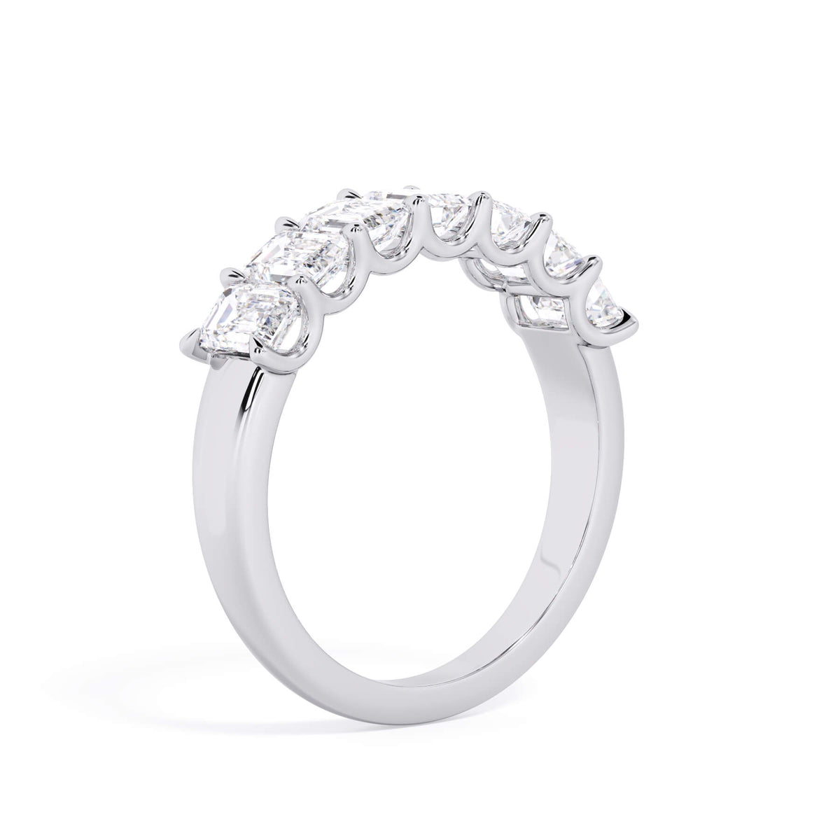 A picture of a seven stone diamond wedding ring with emerald cut diamonds that are U prong set in white gold or platinum on a white background with a slightly angled, through the finger view.
