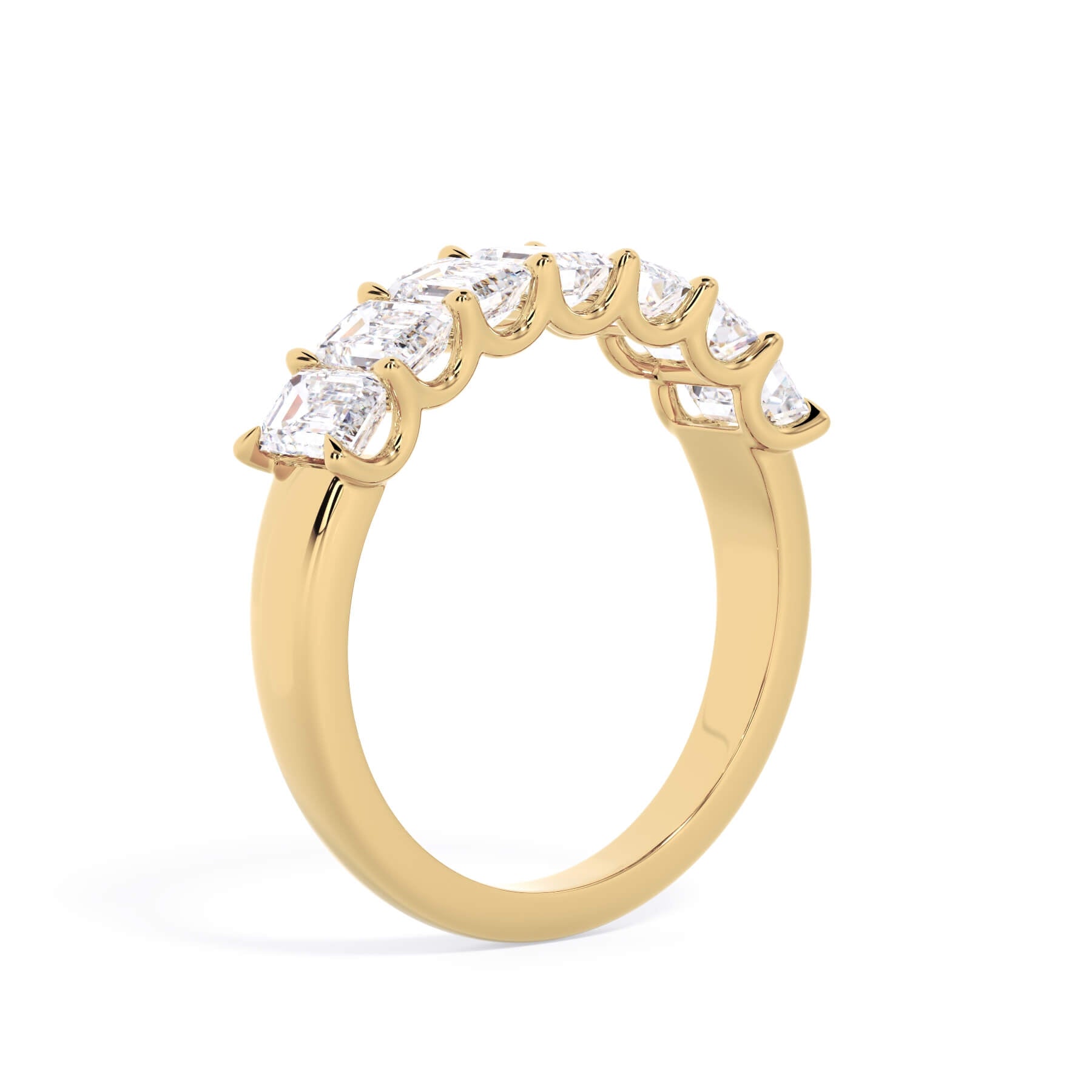 A picture of a seven stone diamond wedding ring with emerald cut diamonds that are U prong set in yellow gold on a white background with a slightly angled, through the finger view.