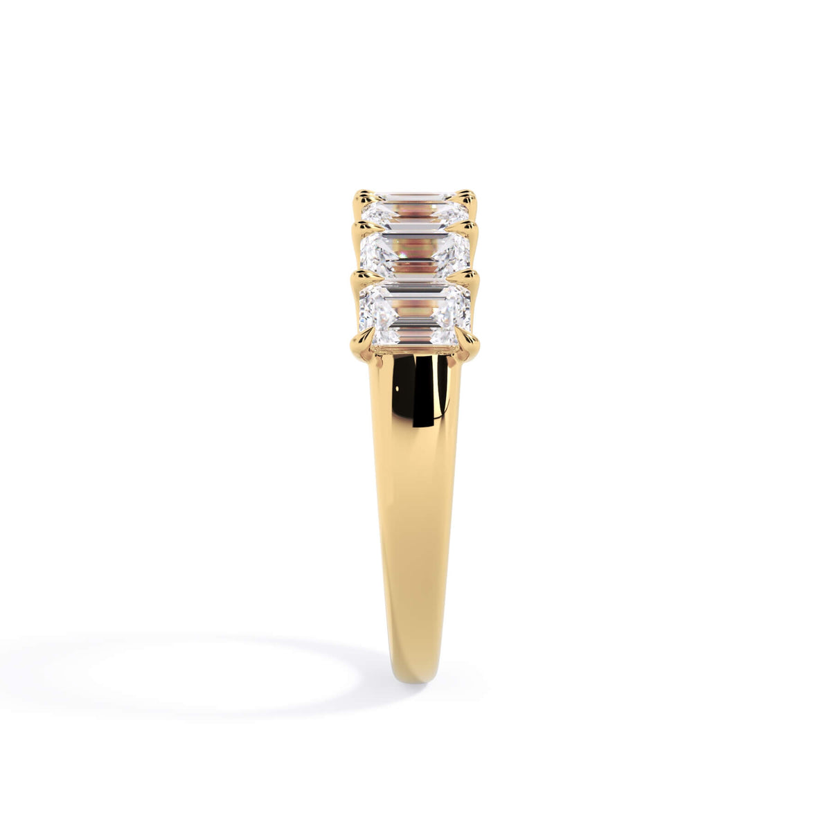 A picture of a seven stone diamond wedding ring with emerald cut diamonds that are U prong set in yellow gold on a white background with a side profile view.