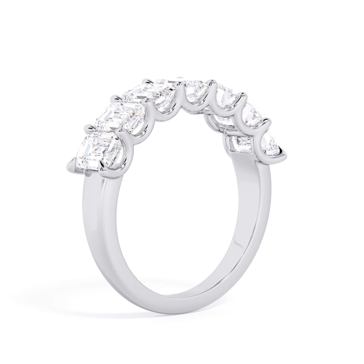 A picture of a seven stone diamond wedding ring with emerald cut diamonds that are U prong set in white gold or platinum on a white background with a slightly angled, through the finger view.