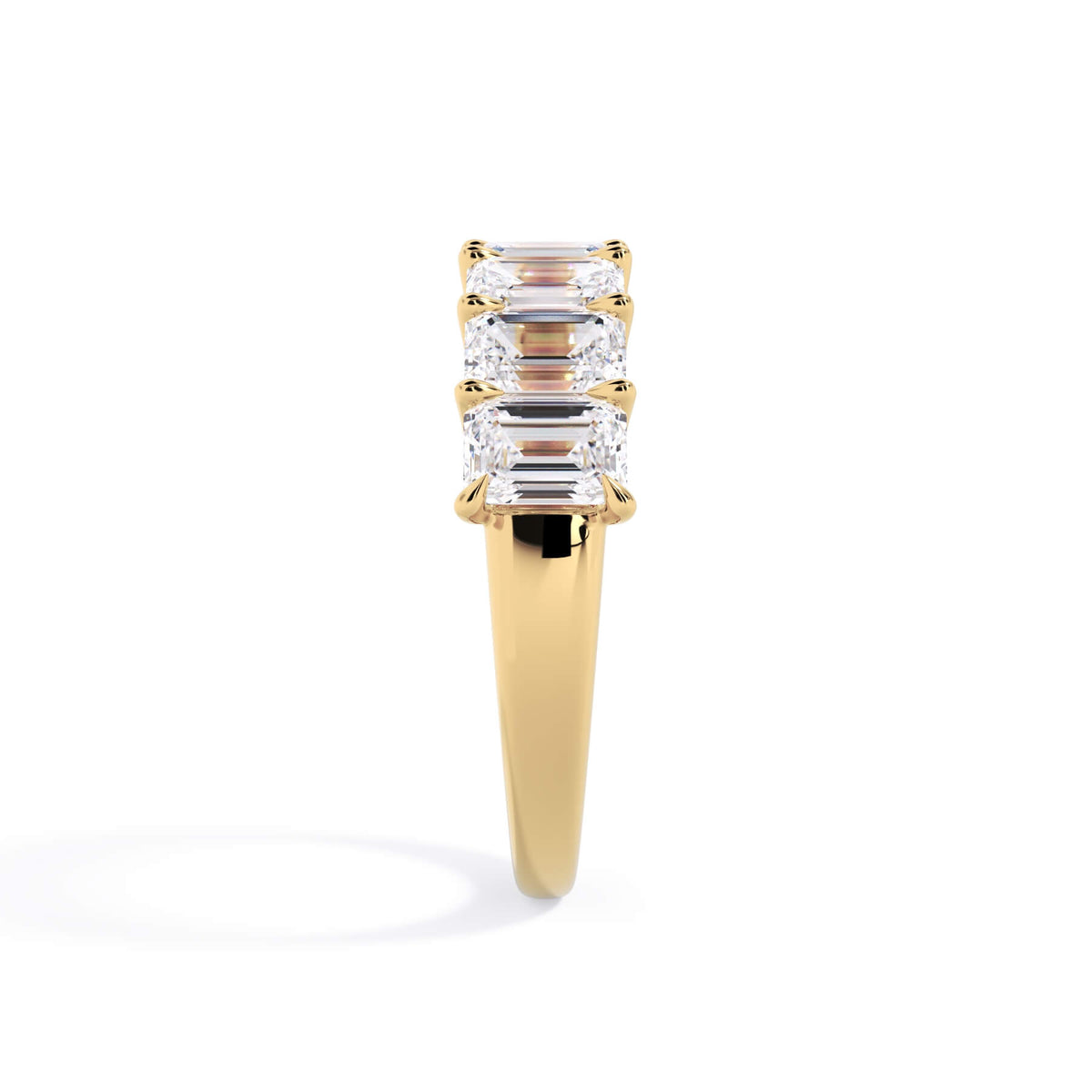 A picture of a seven stone diamond wedding ring with emerald cut diamonds that are U prong set in yellow gold on a white background with a side profile view.