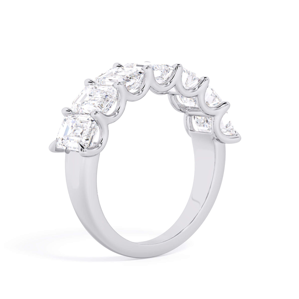 A picture of a seven stone diamond wedding ring with emerald cut diamonds that are U prong set in white gold or platinum on a white background with a slightly angled, through the finger view.