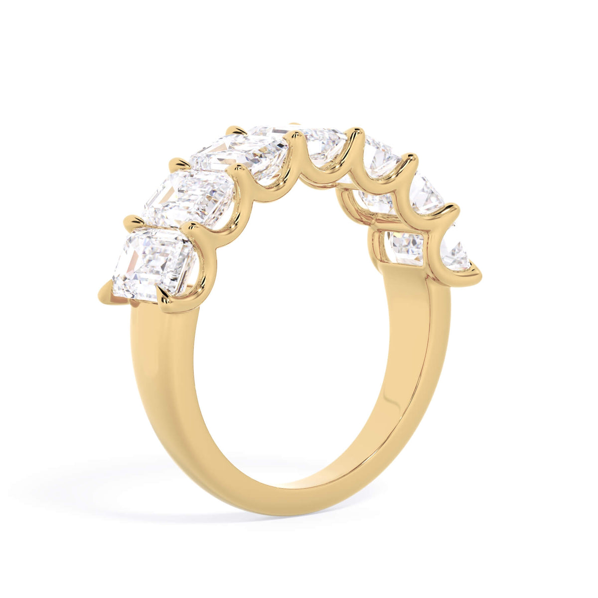 A picture of a seven stone diamond wedding ring with emerald cut diamonds that are U prong set in yellow gold on a white background with a slightly angled, through the finger view.