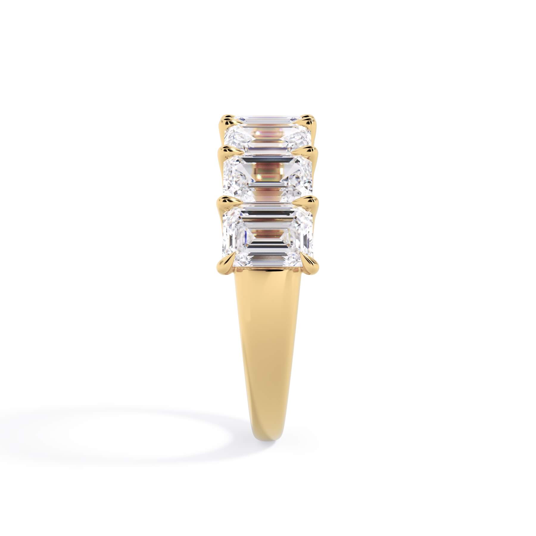 A picture of a seven stone diamond wedding ring with emerald cut diamonds that are U prong set in yellow gold on a white background with a side profile view.