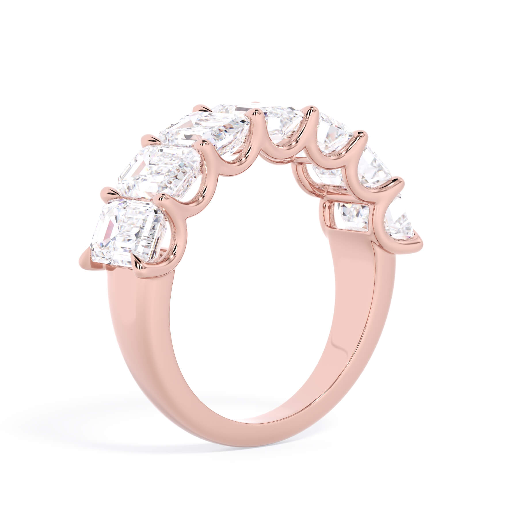 A picture of a seven stone diamond wedding ring with emerald cut diamonds that are U prong set in rose gold on a white background with a slightly angled, through the finger view.