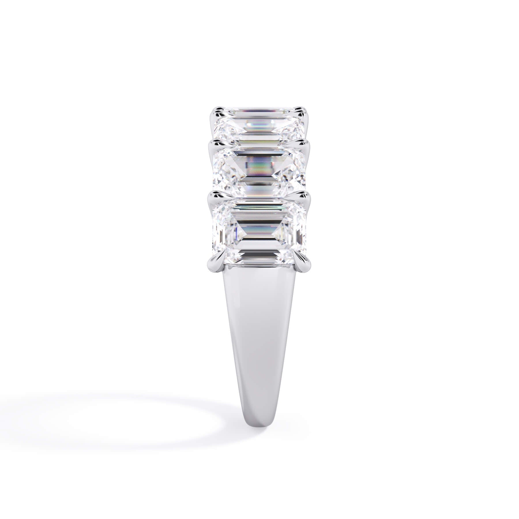 A picture of a seven stone diamond wedding ring with emerald cut diamonds that are U prong set in white gold or platinum on a white background with a side profile view.