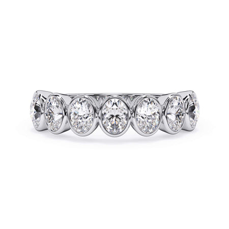 A picture of a seven stone diamond wedding ring with oval shaped diamonds that are bezel set in white gold or platinum on a white background with the ring facing forward, lying down.