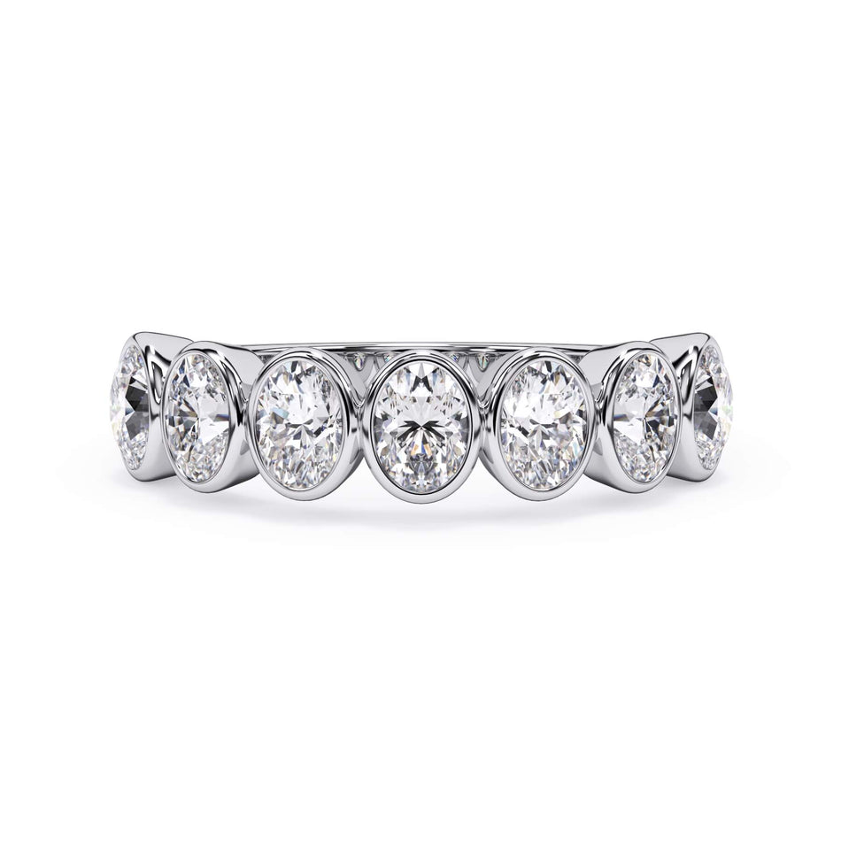 A picture of a seven stone diamond wedding ring with oval shaped diamonds that are bezel set in white gold or platinum on a white background with the ring facing forward, lying down.