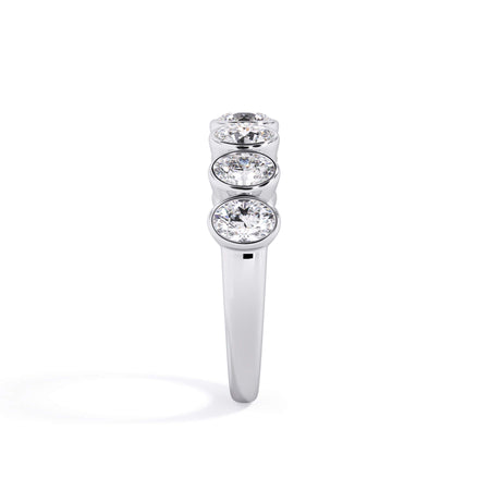 A picture of a seven stone diamond wedding ring with oval shaped diamonds that are bezel set in white gold or platinum on a white background with a side profile view.