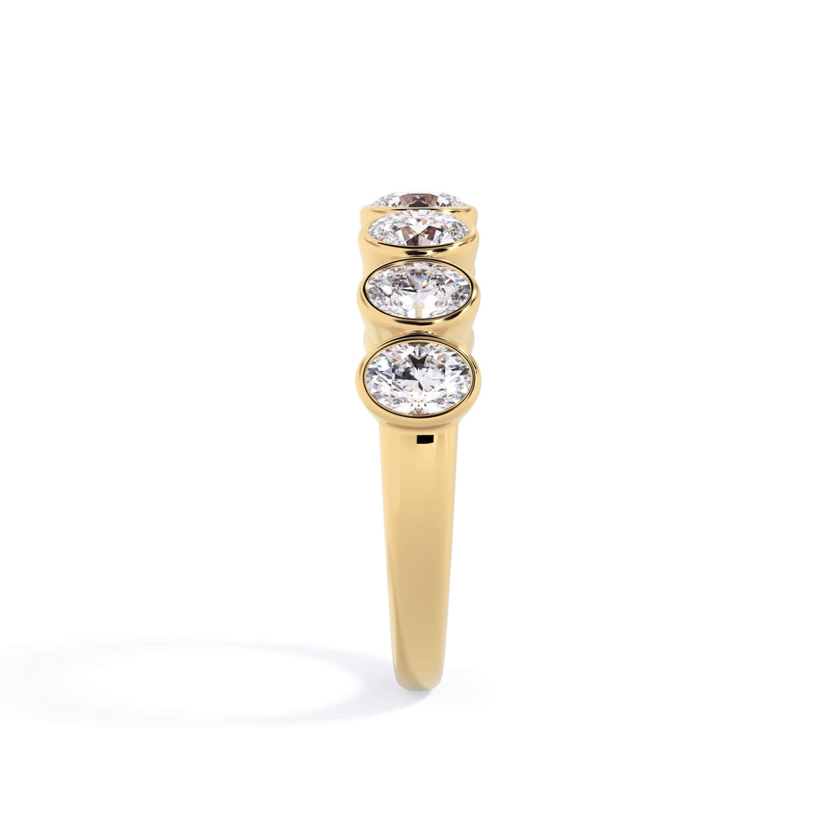 A picture of a seven stone diamond wedding ring with oval shaped diamonds that are bezel set in yellow gold on a white background with a side profile view.