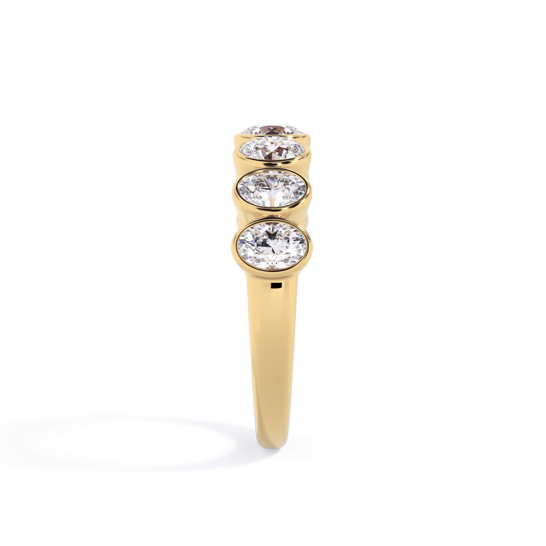 A picture of a seven stone diamond wedding ring with oval shaped diamonds that are bezel set in yellow gold on a white background with a side profile view.