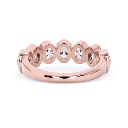 A picture of a seven stone diamond wedding ring with oval shaped diamonds that are bezel set in rose gold on a white background with a view of the underside of the ring.